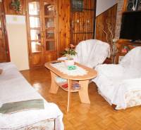 Rodinný dom v obci Čilížska Radváň s veľkým pozemkom - Obývačka s dreveným obkladom, sedačkou, konferenčným stolíkom a dekoráciami v rodinnom dome.