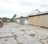 Rodinný dom v obci Čilížska Radváň s veľkým pozemkom - Dlaždený dvor s prístavbou a budovou, vedľa psieho koterca. Rodinný dom v pozadí.