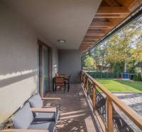 Lukratívne dvoj a štvorizbové byty v Tatranskej Lomnici na prenájom - Balkón 2-izbového bytu v Tatranskej Lomnici s podlahou s dreveným dekorom a záhradným nábytkom.