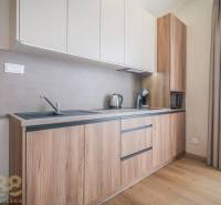 Lukratívne dvoj a štvorizbové byty v Tatranskej Lomnici na prenájom - Kuchyňa v 2-izbovom byte s podlahou s dreveným dekorom a svetlou linkou.