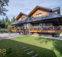 Lukratívne dvoj a štvorizbové byty v Tatranskej Lomnici na prenájom - Dvojposchodový dom s drevenými prvkami a zeleným trávnikom v Tatranskej Lomnici.