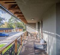 Lukratívne dvoj a štvorizbové byty v Tatranskej Lomnici na prenájom - Balkón 2-izbového bytu v Tatranskej Lomnici s dreveným dekórom a vonkajším sedením.