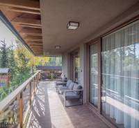 Lukratívne dvoj a štvorizbové byty v Tatranskej Lomnici na prenájom - Balkón 2-izbového bytu v Tatranskej Lomnici s podlahou s dreveným dekorom a výhľadom na zeleň.