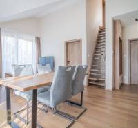 Lukratívne dvoj a štvorizbové byty v Tatranskej Lomnici na prenájom - Obývacia izba s jedálenským stolom a schodiskom v 2-izbovom byte, podlaha s dreveným dekorom.