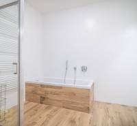 Lukratívne dvoj a štvorizbové byty v Tatranskej Lomnici na prenájom - Kúpeľňa s vaňou a podlahou s dreveným dekorom v 2-izbovom byte.