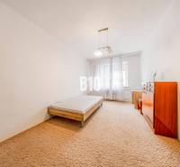 KRÍŽNA: VEĽKORYSÝ 4-IZBOVÝ BYT S RETRO ŠARMOM BLÍZKO CENTRA - Spálňa v 4-izbovom byte s posteľou, komodou a kobercom.