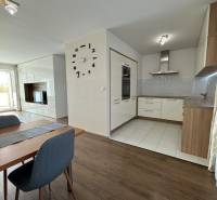 Novinka: Moderný 4-izb. mezonetový byt s balkónom a terasou. Muškát - Jedálenský priestor v 4-izbovom byte s podlahou s dreveným dekorom a kuchyňou v pozadí.