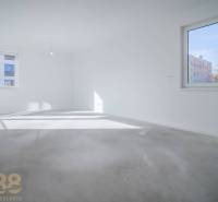 EXKLUZÍVNA PONUKA: Novostavba 3-izb. bytu v projekte Nové Nábrežie - Prázdny izba v 3-izbovom byte so svetlými stenami a veľkými oknami, bez podlahy s dreveným dekorom.