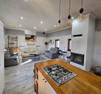 HD reality, predaj rodinný dom Štiavnické Bane - Interiér rodinného domu s krbom a kuchyňou, podlaha s dreveným dekorom.