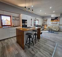 HD reality, predaj rodinný dom Štiavnické Bane - Rodinný dom s podlahou s dreveným dekorom, kuchyňou a obývačkou vybavenou pohodlným sedením.