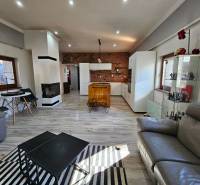 HD reality, predaj rodinný dom Štiavnické Bane - Obývačka v rodinnom dome s krbom, dreveným dekorom a sedacími súpravami.