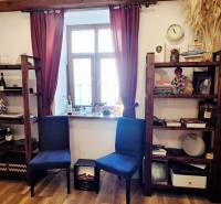 NA PRENÁJOM – odstúpenie vinotéky v srdci Starého Mesta s dušou vína - Knižnice s dekoráciami, stoličky a okno s bordovými závesmi v obchodnom priestore.