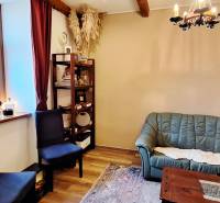 NA PRENÁJOM – odstúpenie vinotéky v srdci Starého Mesta s dušou vína - Obchodné priestory so zelenou sedačkou, poličkami a podlahou s dreveným dekorom.