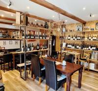 NA PRENÁJOM – odstúpenie vinotéky v srdci Starého Mesta s dušou vína - Interiér obchodných priestorov s podlahou s dreveným dekorom, plný fliaš vína a drevených prvkov.