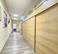 VIACÚČELOVÁ BUDOVA - OBJEKT KOLKÁREŇ - TURČIANSKA, BRATISLAVA - Úzka chodba s drevenými stenami a nástenkami, osvetlené biele podhľady, na Turčianskej.