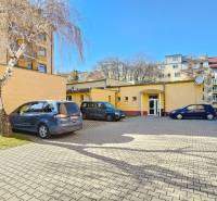 VIACÚČELOVÁ BUDOVA - OBJEKT KOLKÁREŇ - TURČIANSKA, BRATISLAVA - Parkovisko na ulici Turčianska, pred budovou, so zaparkovanými autami a stromami v pozadí.