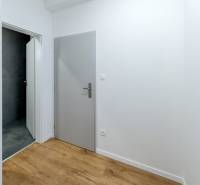 Krásny, priestranný 3i byt 71m2, v tichom dvore, úplne nový - Chodba so sivými dverami, kúpeľňou s tmavými obkladačkami a podlahou s dreveným dekorom.