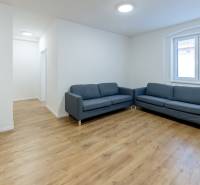 Krásny, priestranný 3i byt 71m2, v tichom dvore, úplne nový - Obývačka s modrou pohovkou a podlahou s dreveným dekorom v 3-izbovom byte.