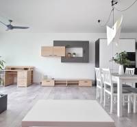 VELKOMETRÁŽNY 1 IZB.AP.BYT- TRNAVSKÁ CESTA, RUŽINOV, BRATISLAVA - Obývacia izba s podlahou s dreveným dekorom, kuchynským kútom a jedálenským stolom v 1-izbovom byte.