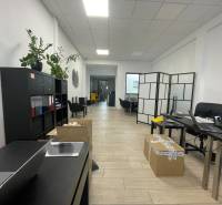 Na prenájom komerčné priestory v priemyselnej zóne v Trenčíne - Obchodné priestory s poličkou, stolmi, kreslami a podlahou s dreveným dekorom.