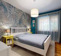 NA PREDAJ ÚTULNÝ, 4 IZBOVÝ RODINNÝ DOM S TERASOU A GARÁŽOU, IŽA - Spálňa v rodinnom dome s palmami na tapete, podlahou s dreveným dekorom a bielym nábytkom.