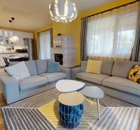 NA PREDAJ ÚTULNÝ, 4 IZBOVÝ RODINNÝ DOM S TERASOU A GARÁŽOU, IŽA - Obývacia izba v rodinnom dome s podlahou s dreveným dekorom, sedačkami a kuchyňou v pozadí.