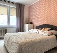 2-izbový byt v Seredi- bez rezervačnej zálohy - Spálňa s bodkovanou tapetou v 2-izbovom byte s veľkými oknami a kvetinovými vankúšmi.
