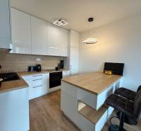 Nový 2-izbový byt na prenájom - Bory - Kuchyňa v 2-izbovom byte s podlahou s dreveným dekorom a barovými stoličkami.