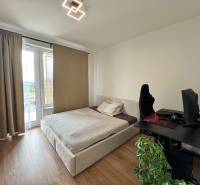 Nový 2-izbový byt na prenájom - Bory - Spálňa v 2-izbovom byte s posteľou, počítačovým stolom a podlahou s dreveným dekorom.