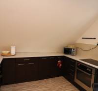 ZNÍŽENÁ cena - viacgeneračný  rodinný dom v Borinke  - Kuchyňa s tmavými skrinkami, varnou doskou a mikrovlnkou v dome na ulici Borinka.