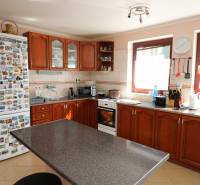 ZNÍŽENÁ cena - viacgeneračný  rodinný dom v Borinke  - Kuchyňa s drevenými skrinkami, spotrebičmi a stolom na ulici Borinka v rodinnom dome.