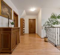 Predaj luxusná 5 izbová Vila,440 m2,pozemok 1061m2,garáž,bazén. - Chodba s dreveným nábytkom, knihovňa, sochy na ulici Hrušovská, schodisko vo vile, rastlina.