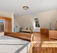 Predaj luxusná 5 izbová Vila,440 m2,pozemok 1061m2,garáž,bazén. - Priestranná spálňa s drevenou podlahou na ulici Hrušovská, obsahujúca nábytok a televízor pri vile.