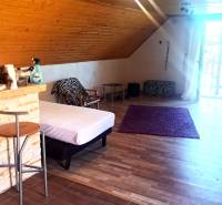 Predaj chaty a chalupy, Levice - Interiér chaty s barovým pultom, posteľou a podlahou s dreveným dekorom.