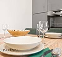 NA PREDAJ MODERNÝ 3-IZB. RD TYPU BUNGALOV V GABČÍKOVE - Jedálenský stôl so stolovaním a pohármi, v pozadí kuchyňa v rodinnom dome.