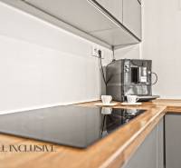 NA PREDAJ MODERNÝ 3-IZB. RD TYPU BUNGALOV V GABČÍKOVE - Kuchyňa v rodinnom dome s kávovarom a varnou doskou na drevenom dekore.