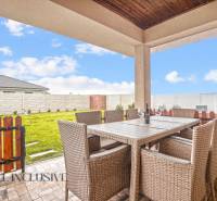 NA PREDAJ MODERNÝ 3-IZB. RD TYPU BUNGALOV V GABČÍKOVE - Terasa rodinného domu v Gabčíkove s ratanovým nábytkom a výhľadom na záhradu.