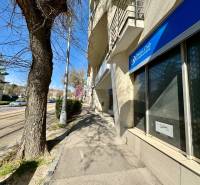 Obchodno- kancelársky priestor s výkladom na Nám. slobody - Budova na ulici Námestie slobody, kancelárie a hlavná cesta, slnečný deň, zaparkované autá.