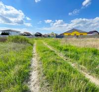 Stavebný pozemok v Bernolákove, Višňová ulica - Pozemok na ulici Višňová s domami v pozadí, ideálny pre bývanie.