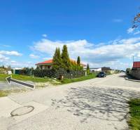 Stavebný pozemok v Bernolákove, Višňová ulica - Rodinné domy na ulici Višňová a pozemky pre bývanie, jasná slnečná obloha.