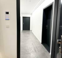 Budova s 8 apartmánmi alebo medicínske centrum, 9 park. miest- Koliba - Chodba s bielymi stenami a šedou podlahou v budove na ulici Na varte.