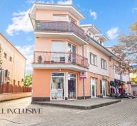 NA PREDAJ 2-IZBOVÝ BYT S 2 BALKÓNMI, DUNAJSKÁ STREDA - Budova na Kukučínovej ulici v Dunajskej Strede so svetlooranžovou fasádou a obchodmi.