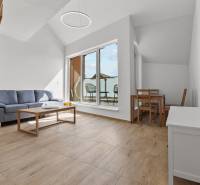 OPAL - NOVÝ a KOMPLETNE ZARIADENÝ 2,5-izbový byt s LODŽIOU a PARKOVANÍ - Obývačka v 2-izbovom byte s podlahou s dreveným dekorom, gaučom a balkónom.