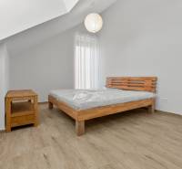 OPAL - NOVÝ a KOMPLETNE ZARIADENÝ 2,5-izbový byt s LODŽIOU a PARKOVANÍ - Spálňa v 2-izbovom byte s posteľou, dreveným nábytkom a podlahou s dreveným dekorom.
