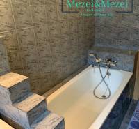 Na predaj útulný 2-izbový byt, Bratislava – Nové Mesto - Kúpeľňa so schodíkmi a vaňou obklopená sivými obkladmi v 2-izbovom byte.