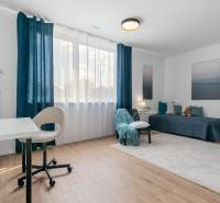 BÝVANIE VO VILA DOME - POSLEDNÝ VOĽNÝ 3-IZBOVÝ BYT SO ZÁHRADOU - Svetlá izba s pracovným stolom, posteľou a podlahou s dreveným dekorom v 3-izbovom byte.