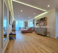 REZERVOVANÉ - 3i, OV, 71m2 + loggia, Lomonosovova, dizajnový, zariaden - Obývacia izba s podlahou s dreveným dekorom v 3-izbovom byte, pohodlnou sedačkou a dekoráciami.