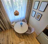 REZERVOVANÉ - 3i, OV, 71m2 + loggia, Lomonosovova, dizajnový, zariaden - Jedálenský kút s okrúhlym stolom, kreslami a podlahou s dreveným dekorom v 3-izbovom byte.