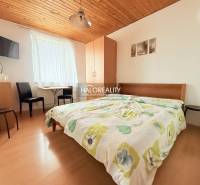 Prenájom, penzión Podhájska - EXKLUZÍVNE HALO REALITY - Hotelová izba s dvojposteľou, televízorom, stolom a podlahou s dreveným dekorom.