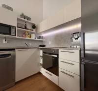 Prenájom moderného 2-izbového bytu v centre Komárna, 40 m² – Petőfiho  - Kuchyňa v 2-izbovom byte s podlahou s dreveným dekorom a modernými spotrebičmi.